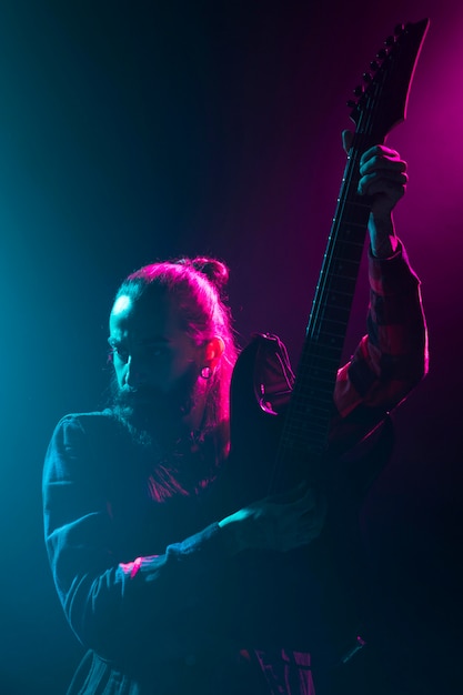 Artista tocando guitarra no palco, plano médio