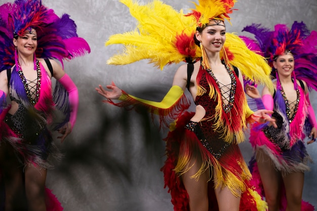 Artistas de cabaré feminino dançando nos bastidores em trajes de penas