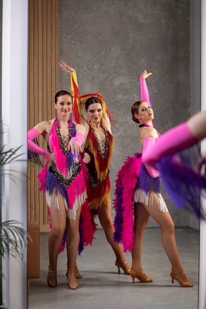 Artistas de cabaré feminino posando nos bastidores em trajes de penas