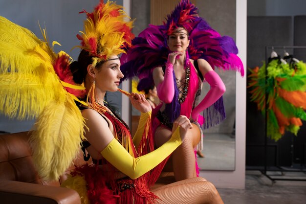 Artistas de cabaré feminino posando nos bastidores em trajes de penas