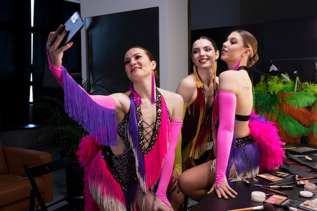 Artistas de cabaré feminino tomando uma selfie juntos nos bastidores em trajes