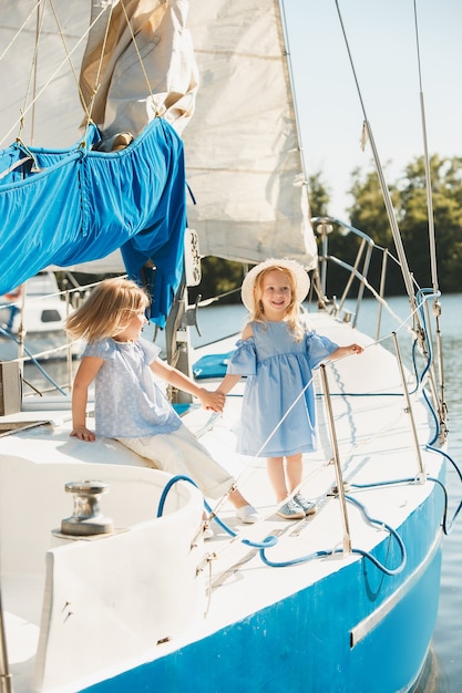 As crianças a bordo do iate do mar. As meninas adolescentes ou crianças ao ar livre. Roupas coloridas. Conceitos de moda infantil, verão ensolarado, rio e feriados.