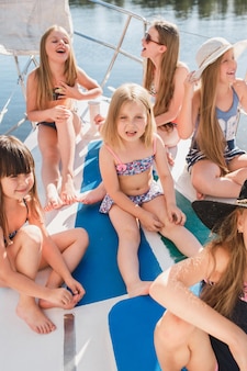 As crianças a bordo do iate do mar. as meninas adolescentes ou crianças ao ar livre. roupas coloridas. conceitos de moda infantil, verão ensolarado, rio e feriados.