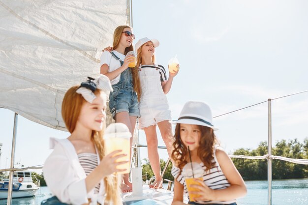 As crianças a bordo do iate marítimo bebendo suco de laranja