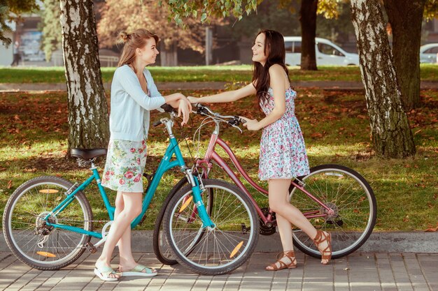 As duas meninas com bicicletas no parque