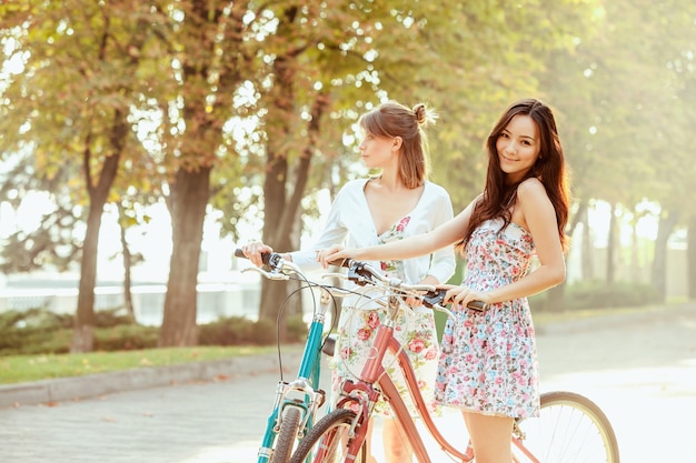 As duas meninas com bicicletas no parque