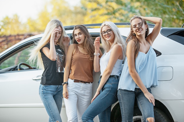 As jovens mulheres em pé perto do carro