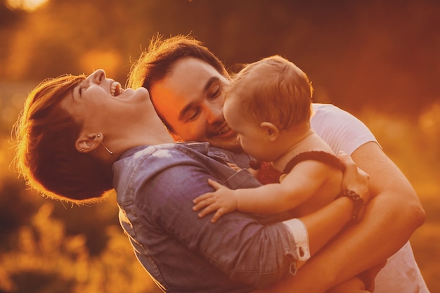 Foto grátis as luzes do pôr-do-sol brilham sobre os pais beijando e sua filha pequena