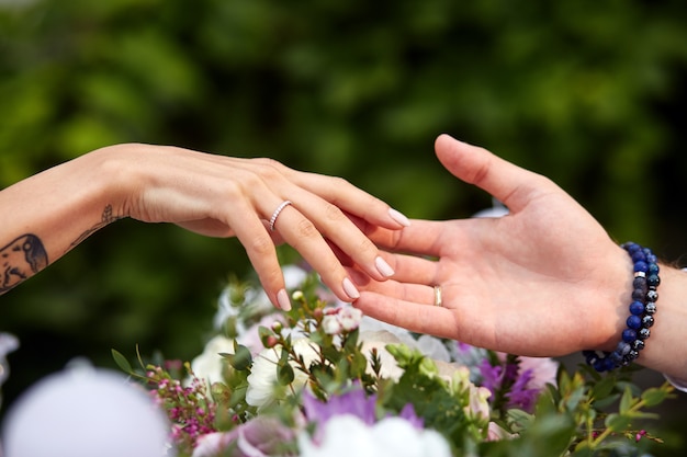 As mãos do homem e da mulher tocam-se mutuamente sobre um buquê