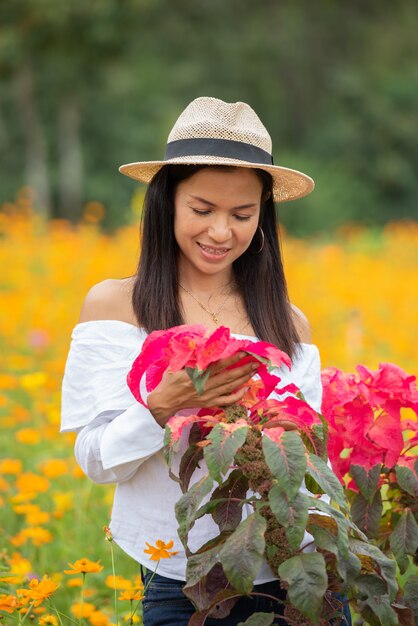 As mulheres asiáticas estão apreciando flores vermelhas no parque.