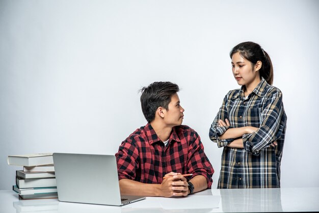 As mulheres ensinam os homens a trabalhar com laptops no trabalho.