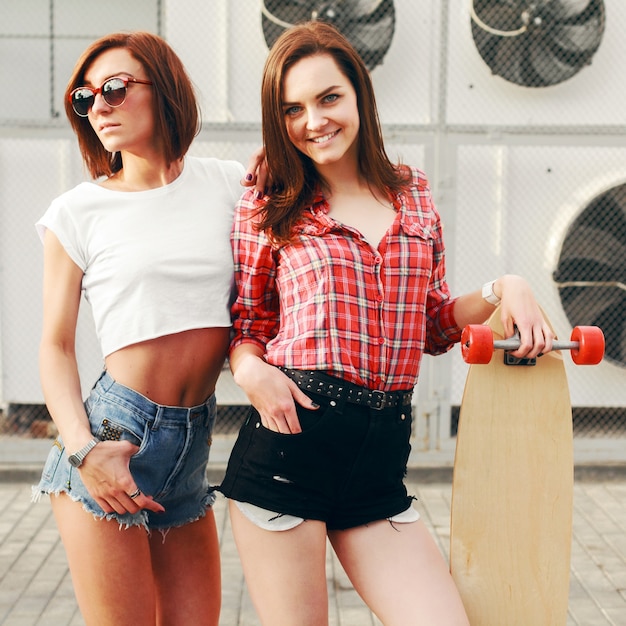 Foto grátis as mulheres felizes em shorts com um skate ao ar livre