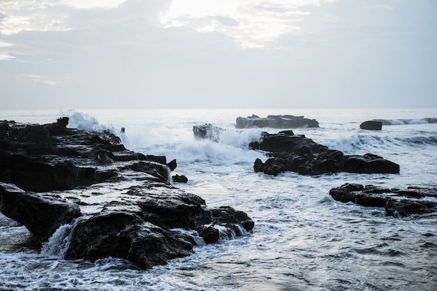 as ondas do oceano estão quebrando contra as rochas. espirrando ondas do mar ao pôr do sol.