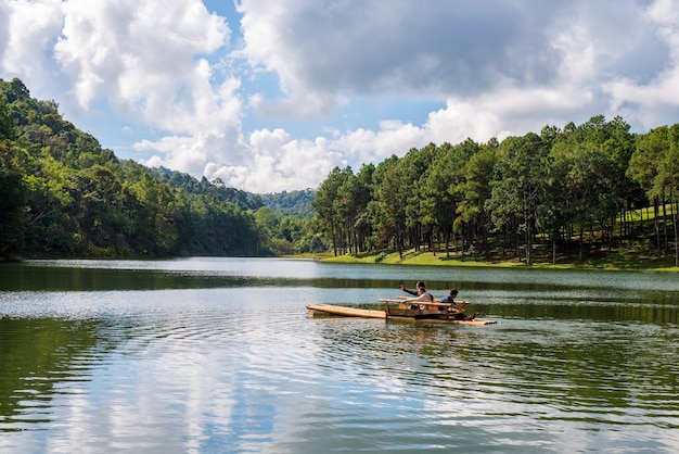 As pessoas em um barco em um lago com árvores