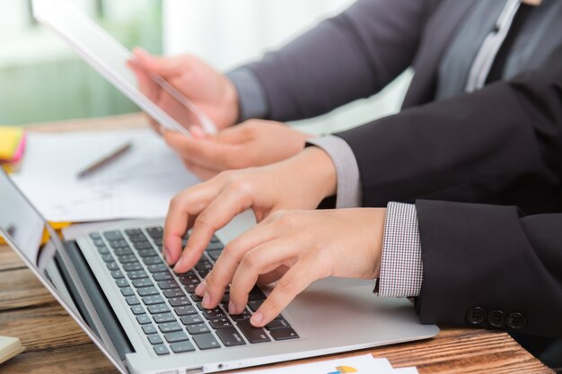 As pessoas que trabalham em uma mesa de madeira com um laptop e um tablet