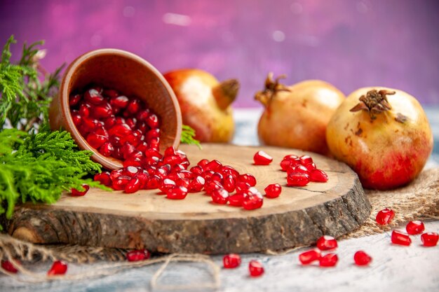 As romãs de frente espalharam sementes de romã em uma tigela na placa de madeira da árvore no rosa