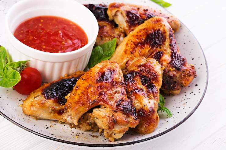 Foto grátis asas de frango assadas ao estilo asiático e molho de tomate no prato