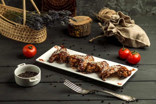 Asas de frango cozidas em molho teriyaki, guarnecido com gergelim