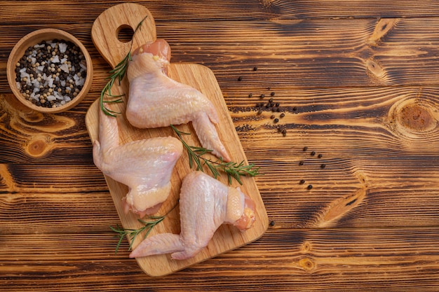 Foto grátis asas de frango cru na superfície de madeira escura.