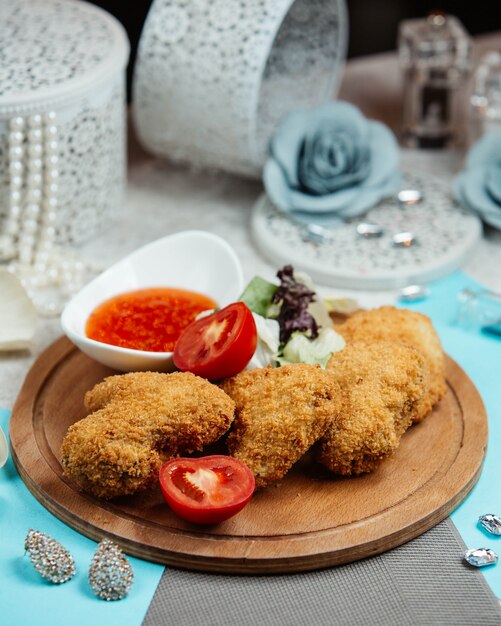 Asas de frango frito crocantes, servidas com alface, tomate e molho de pimenta doce