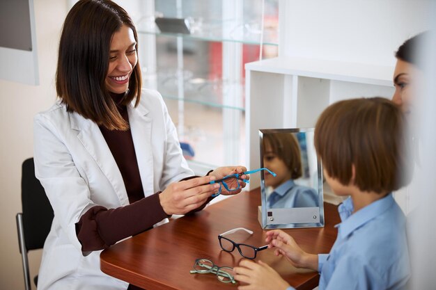 Assistente médico amigável apresentando óculos azuis para uma criança