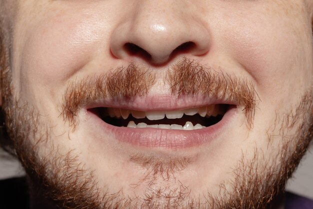 Assustada. Perto do rosto de um jovem caucasiano bonito com barba ruiva, concentre-se na boca.