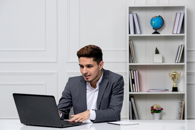 Atendimento ao cliente bonitinho em terno de escritório com computador digitando no teclado