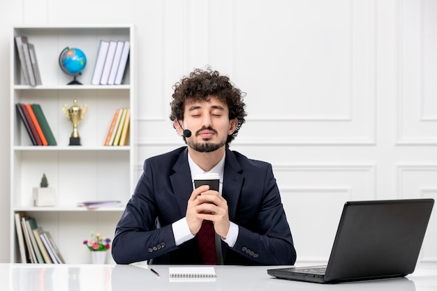 Atendimento ao cliente, jovem bonito em terno de escritório com laptop e fone de ouvido, olhos fechados com café