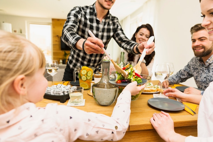 Foto grátis atento homem colocando salada para criança