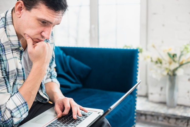 Atento homem olhando para laptop em casa