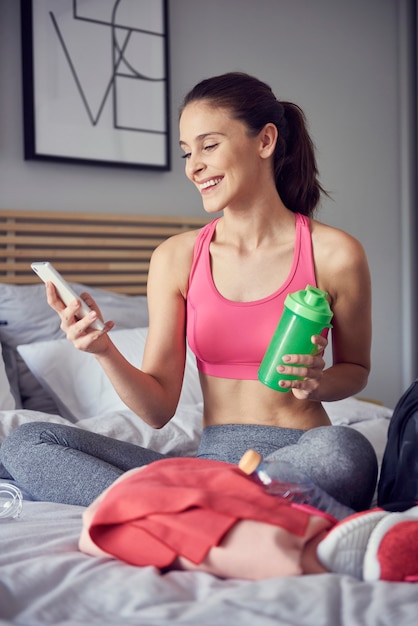 Atleta alegre usando um telefone celular no quarto