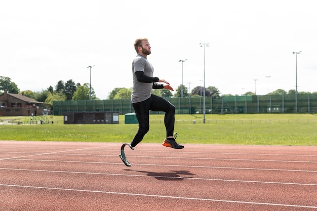 Foto grátis atleta com prótese pulando tiro completo