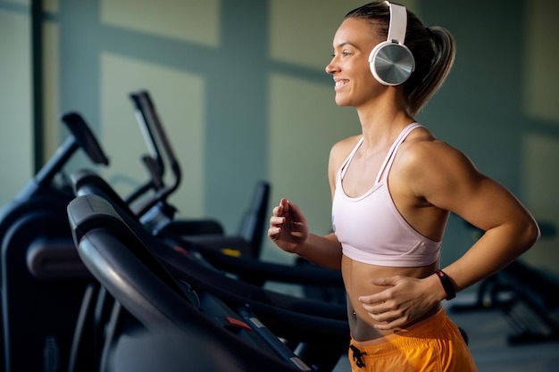 Foto grátis atleta feminina feliz correndo na esteira em uma academia