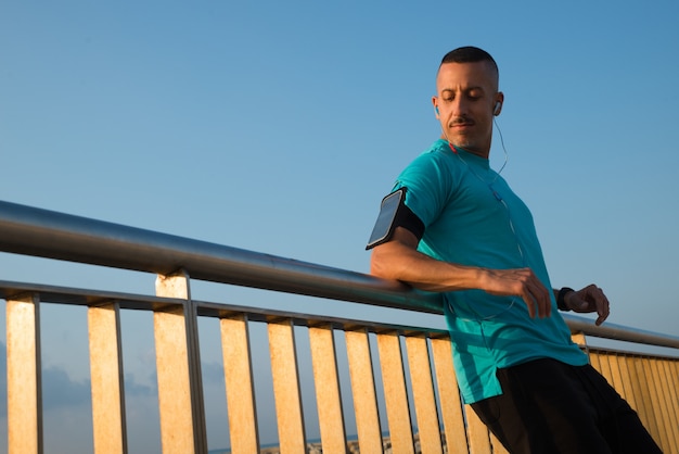 Atleta grave com fones de ouvido apoiado na ponte