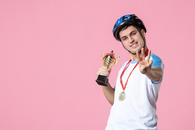 Atleta masculino com roupas esportivas segurando uma taça dourada com capacete