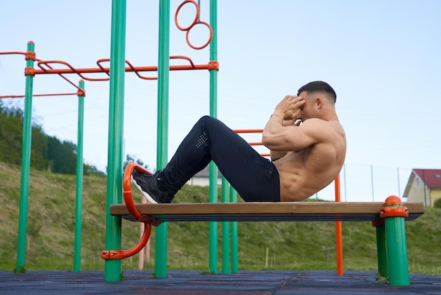 Atleta masculino com torso nu fazendo exercícios abdominais