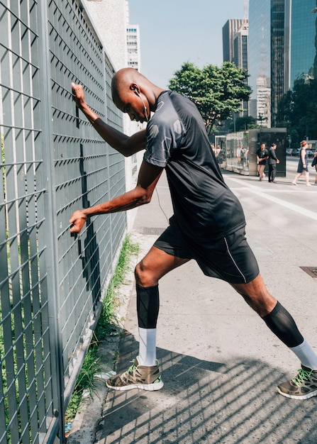 Foto grátis atleta masculino jovem africano, exercitando ao ar livre na cidade