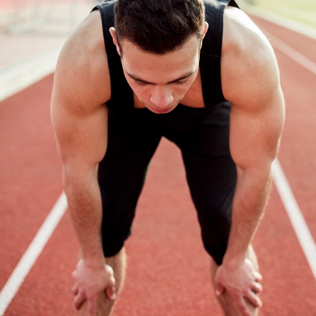 Atleta masculino musculoso em pé na pista de corrida