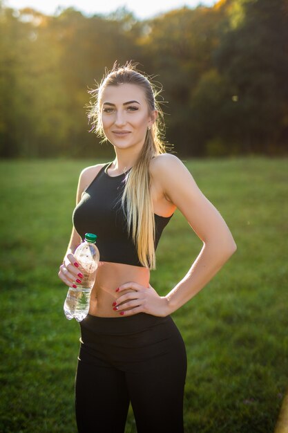 Atleta mulher faz uma pausa, ela bebendo água, em uma corrida em um dia quente