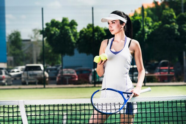 Atleta mulher no sportswear segurando raquete e bolas