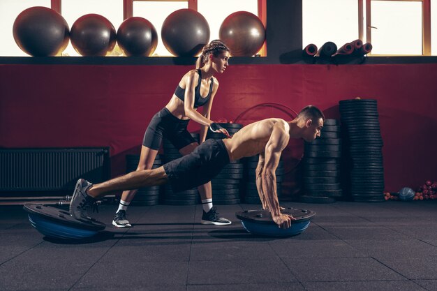 Atlético homem e mulher com um halteres treinando e praticando no ginásio.