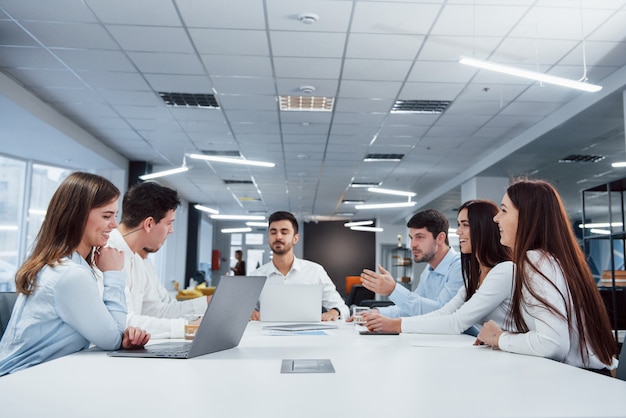 Atmosfera amigável. Grupo de jovens freelancers no escritório tem conversa e sorrindo