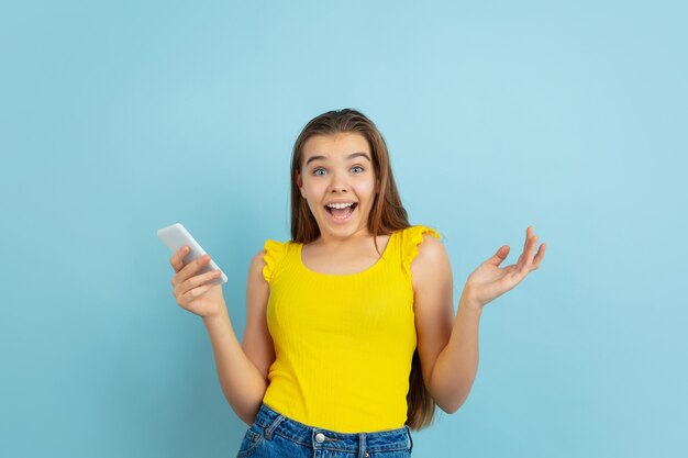 Atônito. Retrato de menina adolescente branca isolado em azul