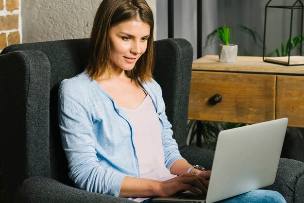 Atraente, mulher, browsing, laptop, em, poltrona