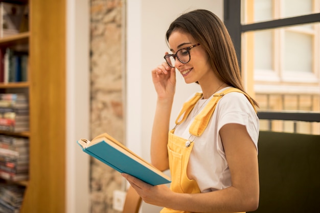 Foto grátis atraente, mulher jovem, livro leitura, em, biblioteca