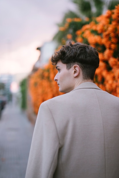 Atrás do jovem andando perto de flores