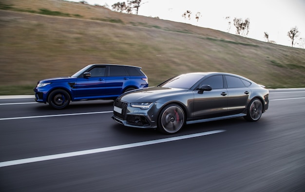 Automobilismo de um jipe azul e um carro esporte cinza sedan.