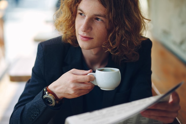 Avermelhado jovem empresário bebendo café durante a leitura