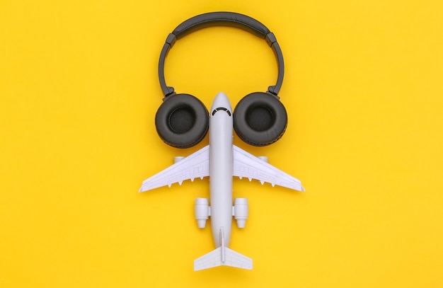 Avião de brinquedo com fones de ouvido estéreo em fundo amarelo. vista do topo