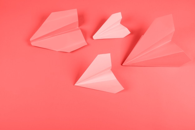 Avião de papel coral e rosa em fundo colorido